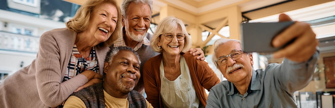 Diverse group of happy senior people taking selfie with cell phone.
